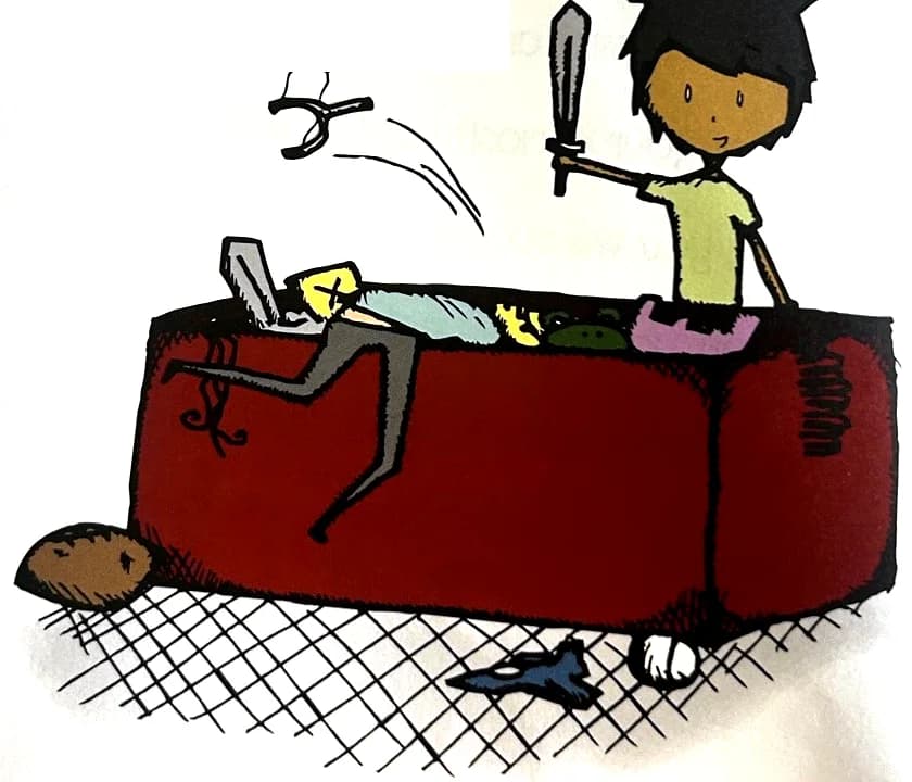 A boy holds up a toy sword inside a big red toy chest full of toys.