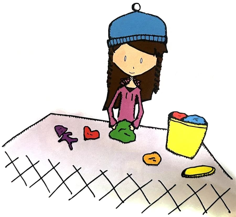 A girl squishes green playdough at a table covered in playdough shapes.